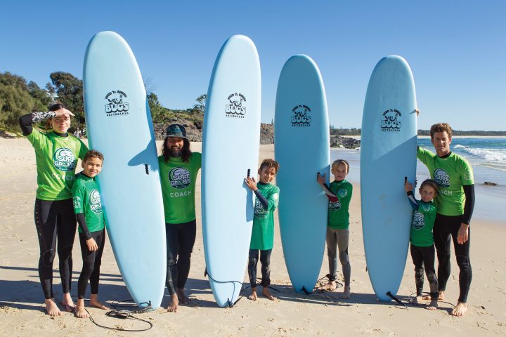 a group of people standing on a beach posing for the camera