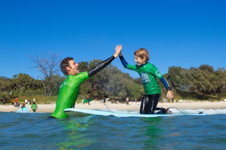 a young girl riding a wave on a surfboard in the water