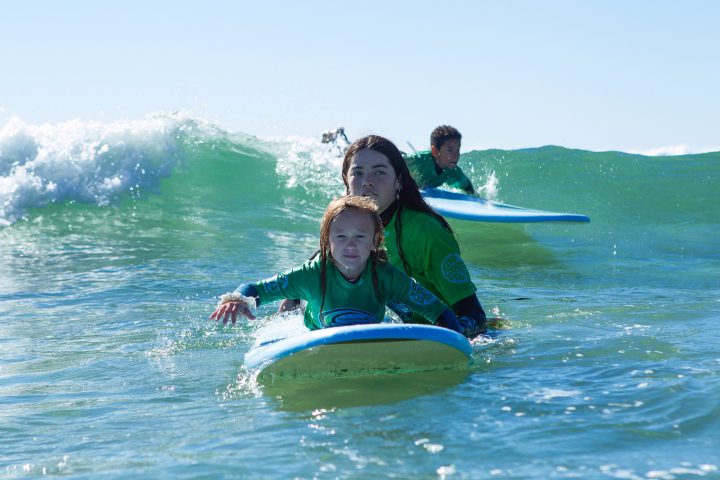 a young girl riding a wave on a surfboard in the ocean